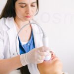 A cosmetologist performs a facial using ultrasonic equipment in a modern spa setting.