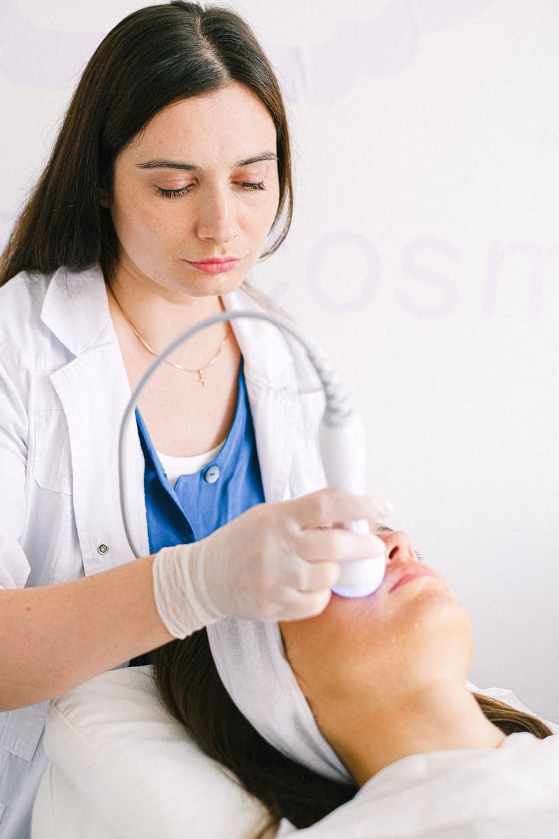 A cosmetologist performs a facial using ultrasonic equipment in a modern spa setting.